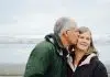 man kissing woman on check beside body of water