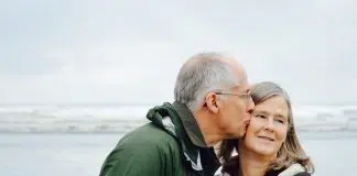 man kissing woman on check beside body of water